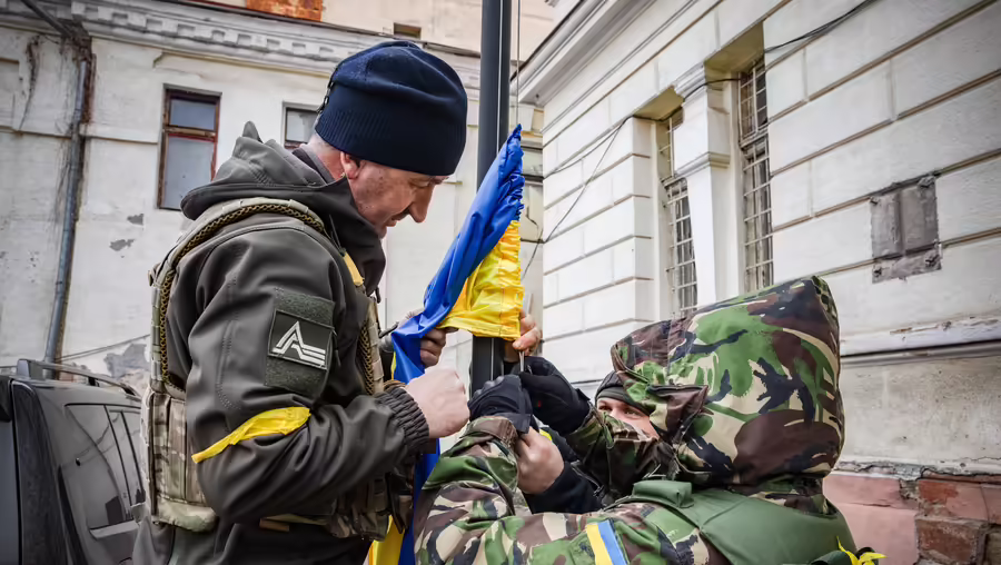 Ukrainische Freiwillige der Territorialverteidigung und ein Soldat hissen die ukrainische Nationalflagge am 7. März 2022 in Odessa (Ukraine). / © Francesca Volpi (KNA)